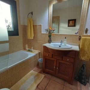 a bathroom with a tub and a sink and a mirror at Sa Bardella in Sant Joan de Labritja