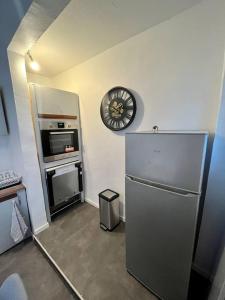 a kitchen with a refrigerator and a clock on the wall at Super appartement chaleureux à 30min de Paris in Gagny