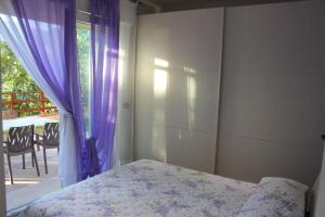 a bedroom with a bed and a window with purple curtains at Casa Simone in Omegna