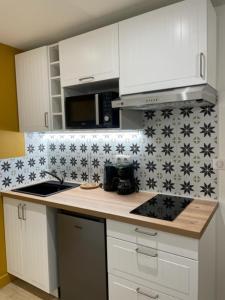 una cocina con armarios blancos y azulejos blancos y negros en Superbe Studio Meublé - Houdan, en Houdan