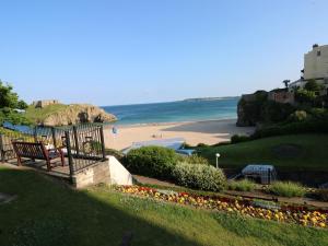 a bench sitting on a hill next to a beach at Westwinds in Tenby