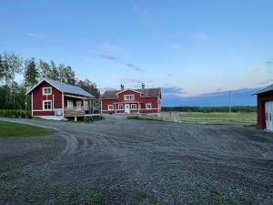 a red house and a barn with a dirt road at Backes Lillstuga in Borlänge