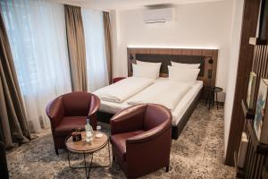 une chambre d'hôtel avec un lit et deux chaises dans l'établissement Hotel Zumnorde Am Anger, à Erfurt