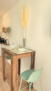 uma mesa com uma cadeira verde e um vaso com penas em Paisible Provence avec terrasse sur vue piscine em Éguilles