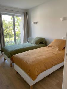 1 dormitorio con 2 camas y ventana en Magnifique appartement climatisé de 87m², à 100m de la plage, en Antibes