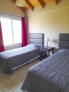 1 dormitorio con 2 camas y mesa con lámpara en Los Robles Apart Hotel en Sierra de la Ventana