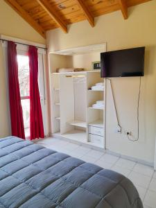 1 dormitorio con 1 cama y TV de pantalla plana en Los Robles Apart Hotel en Sierra de la Ventana