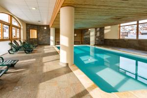 a swimming pool in a building with chairs around it at Résidence Lagrange Vacances L'Ecrin des Sybelles in La Toussuire