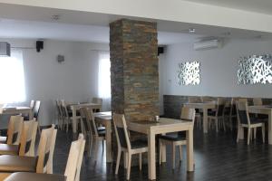 a dining room with tables and chairs and a brick pillar at Penzion Bowten in Sečovce