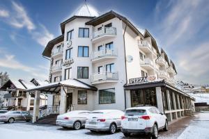 a large white building with cars parked in front of it at Continental in Bukovel