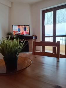 sala de estar con mesa y TV en Vista Panoramica ALTOPIANO DELLE ROCCHE en Terranera