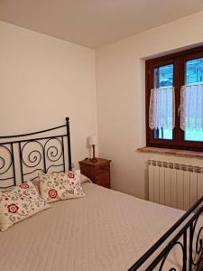 1 dormitorio con 1 cama con 2 almohadas y ventana en Vista Panoramica ALTOPIANO DELLE ROCCHE en Terranera