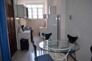 una piccola cucina con tavolo in vetro e sedie di Plateau Apartment a Praia