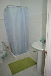 a bathroom with a shower curtain and a toilet and a sink at Plateau Apartment in Praia