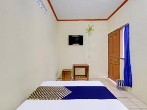 a bedroom with a bed and a tv and a window at SPOT ON 92220 Sari Laut in Glagah