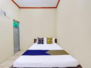 a bedroom with a large bed with blue and yellow pillows at SPOT ON 92220 Sari Laut in Glagah