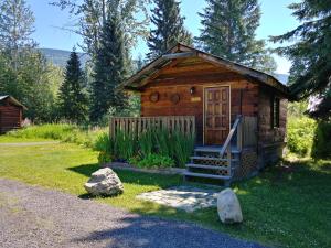 a small log cabin with a porch and a door at Wolfwood Guest Ranch in Clearwater