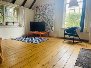 uma sala de estar com uma televisão, uma mesa e uma cadeira em Heerlijke boerderij bij Veluwezoom in het Oude Dieren em Dieren