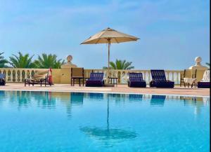una piscina con sillas y sombrilla en Full sea view Studio high floor, en Ras al Khaimah
