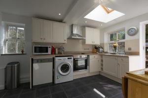 a kitchen with white cabinets and a washer and dryer at 15 Boscaswell Downs in Penzance