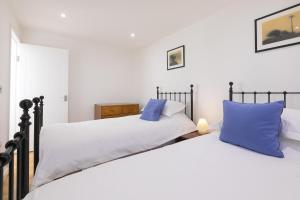 two beds with blue pillows in a bedroom at 15 Boscaswell Downs in Penzance