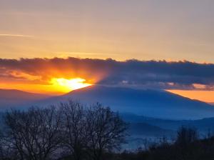 una vista di una montagna con il sole nascosto dietro le nuvole di Casale Mille e una Notte a Perugia