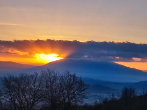 Blick auf einen Berg mit der Sonne hinter Wolken in der Unterkunft Casale Mille e una Notte in Perugia