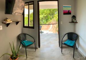 - un couloir avec deux chaises et une porte donnant sur une terrasse dans l'établissement Casa Allegria, à Tamarindo