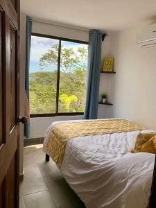 - une chambre avec un lit et une grande fenêtre dans l'établissement Casa Allegria, à Tamarindo