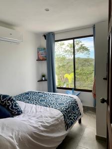 een slaapkamer met een bed en een groot raam bij Casa Allegria in Tamarindo