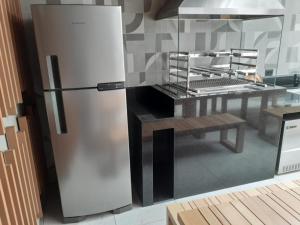 una nevera de acero inoxidable en una cocina con mesa en Smart Studio Mobiliado na Vila Mariana, en São Paulo