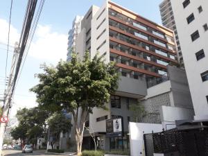 un edificio alto con un árbol delante de él en Smart Studio Mobiliado na Vila Mariana, en São Paulo