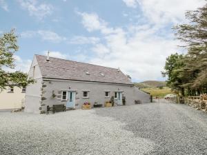 a white cottage with a gravel driveway at Ffynnon Bach in Caernarfon