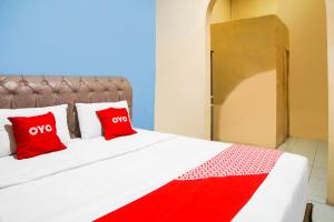 Una cama con dos almohadas rojas. en SUPER OYO 92076 Sky Residence Cengkeh, en Medan