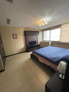 1 dormitorio con cama, escritorio y ventana en Departamento Real Suite, en Guayaquil