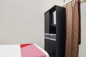 1 dormitorio con armario negro y TV en SUPER OYO 92076 Sky Residence Cengkeh, en Medan