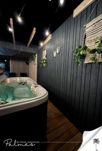La salle de bains est pourvue d'un bain à remous avec des plantes sur le mur. dans l'établissement Palmes Pirmas Sezonas Palanga, à Palanga