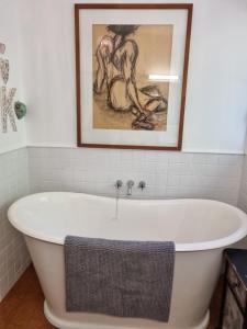 a bath tub in a bathroom with a painting on the wall at Whiteacres in Invercargill