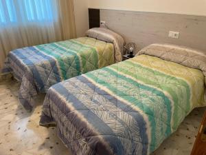 Habitación con 2 camas y mantas de colores. en Casa turismo rural Becar en Corullón