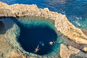 een persoon die zwemt in een grot in de oceaan bij Home Mood B&B in Għarb