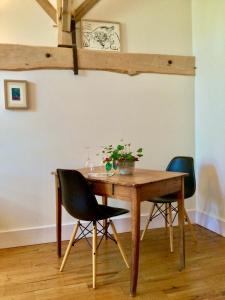 una mesa de madera con 2 sillas y una mesa con una planta. en Belle et spacieuse chambre d’hôtes avec piscine, en Savignac-de-Duras