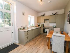 a kitchen with a wooden table and a wooden floor at Hope House Stables in Tiverton