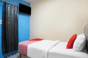 um quarto com uma cama branca e uma televisão na parede em SUPER OYO 92075 Sky Residence Mawar em Sunggal
