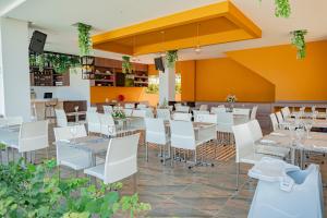um restaurante com mesas brancas e cadeiras brancas em Hotel Explore Caño Dulce em Tubará