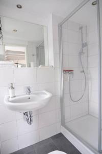 a white bathroom with a sink and a shower at Wertschätzer II - Unter der Wehme in Detmold +11 photos