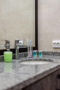 a bathroom counter with a sink with glasses on it at Сердце города 1комн ЖК Молодёжный in Almaty +23 photos