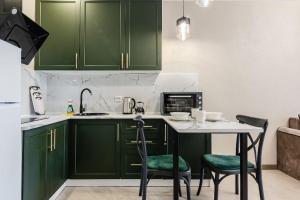 a kitchen with green cabinets and a table and chairs at Сердце города 1комн ЖК Молодёжный in Almaty