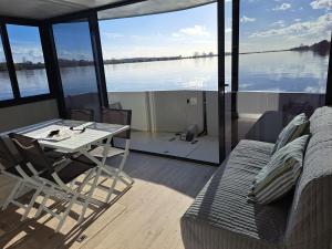 a room with a table and a couch and a view of the water at Casa barco Valada in Morgado