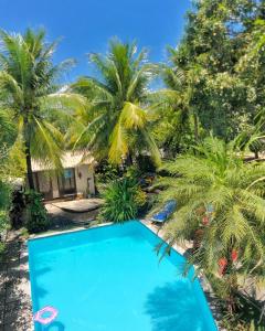 a blue swimming pool with palm trees in the background at Exclusive Guest House in Porto De Galinhas