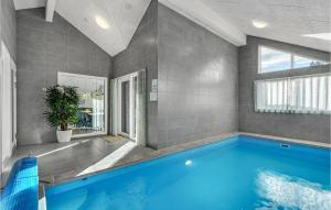 a large swimming pool in a room with a large window at Gorgeous Home In Blåvand With Sauna in Blåvand